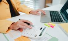 Attività di calcolo in ufficio con PC e calcolatrice.