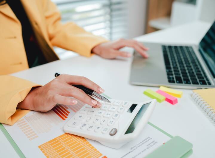 Attività di calcolo in ufficio con PC e calcolatrice.