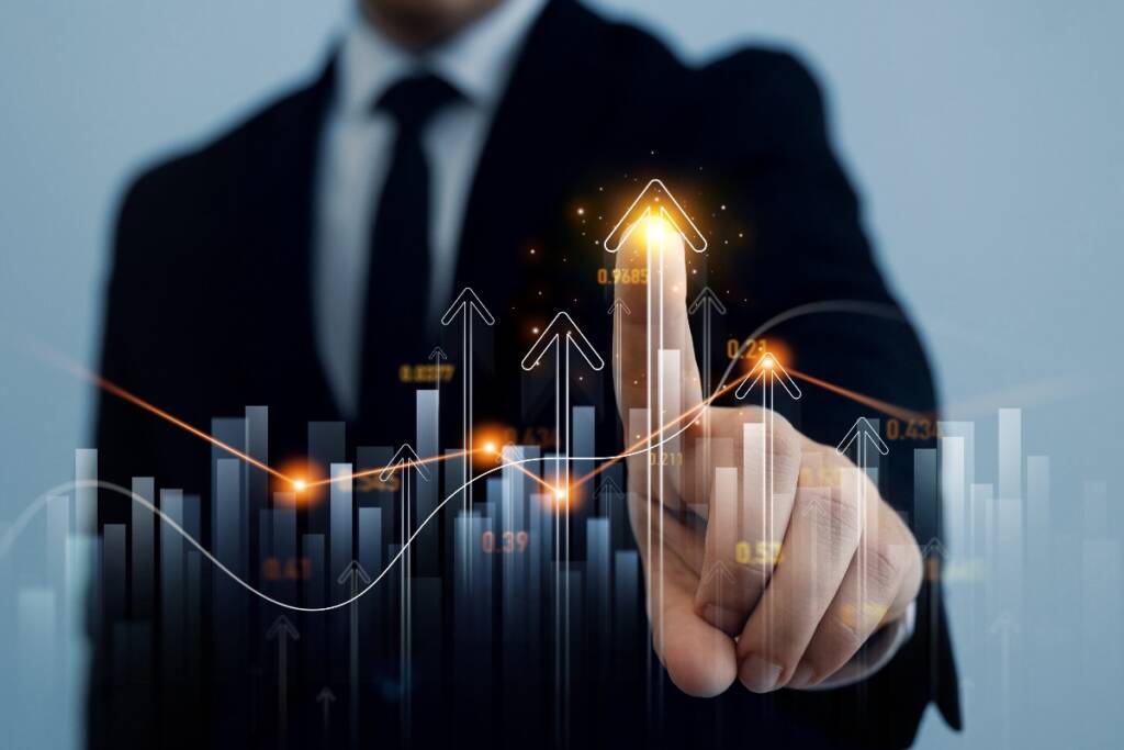 Analisi positiva: uomo in giacca e cravatta indica un grafico di borsa in crescita.