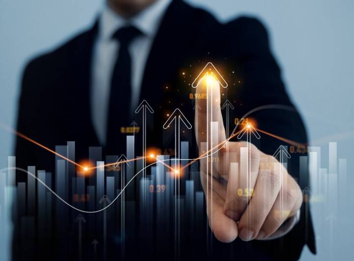 Analisi positiva: uomo in giacca e cravatta indica un grafico di borsa in crescita.