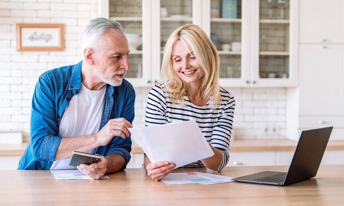 Gestione spese: marito e moglie controllano una bolletta insieme al computer.