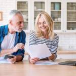 Gestione spese: marito e moglie controllano una bolletta insieme al computer.