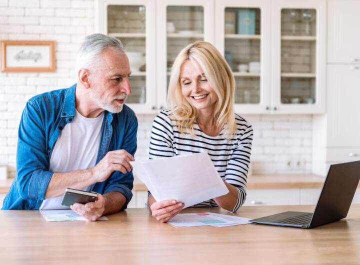 Gestione spese: marito e moglie controllano una bolletta insieme al computer.